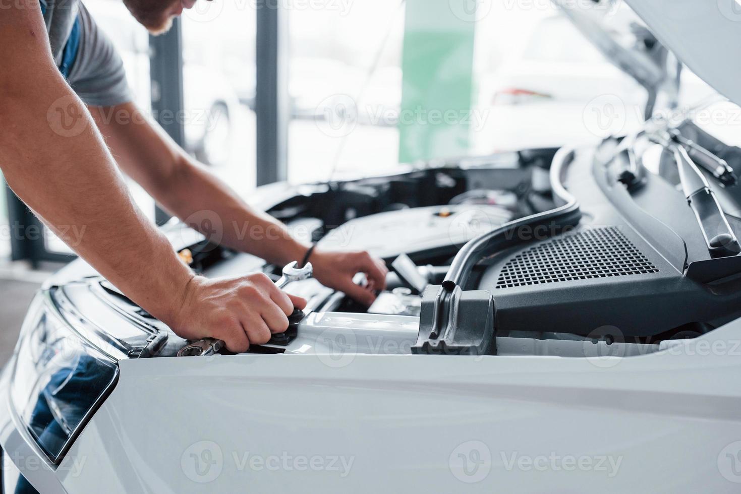 prozess der reparatur des autos nach einem unfall. Mann, der mit dem Motor unter der Motorhaube arbeitet foto