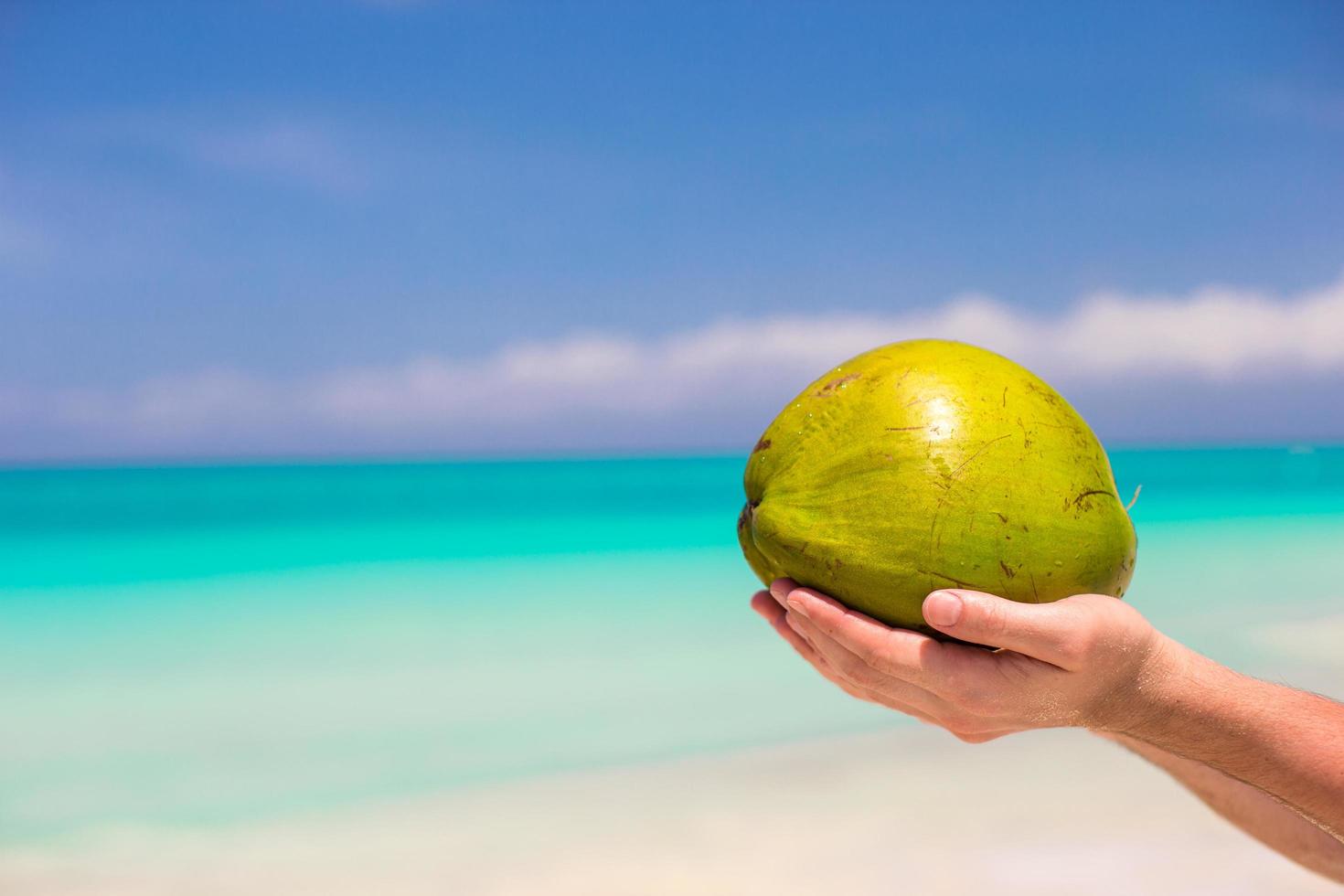 Person, die eine Kokosnuss an einem Strand hält foto