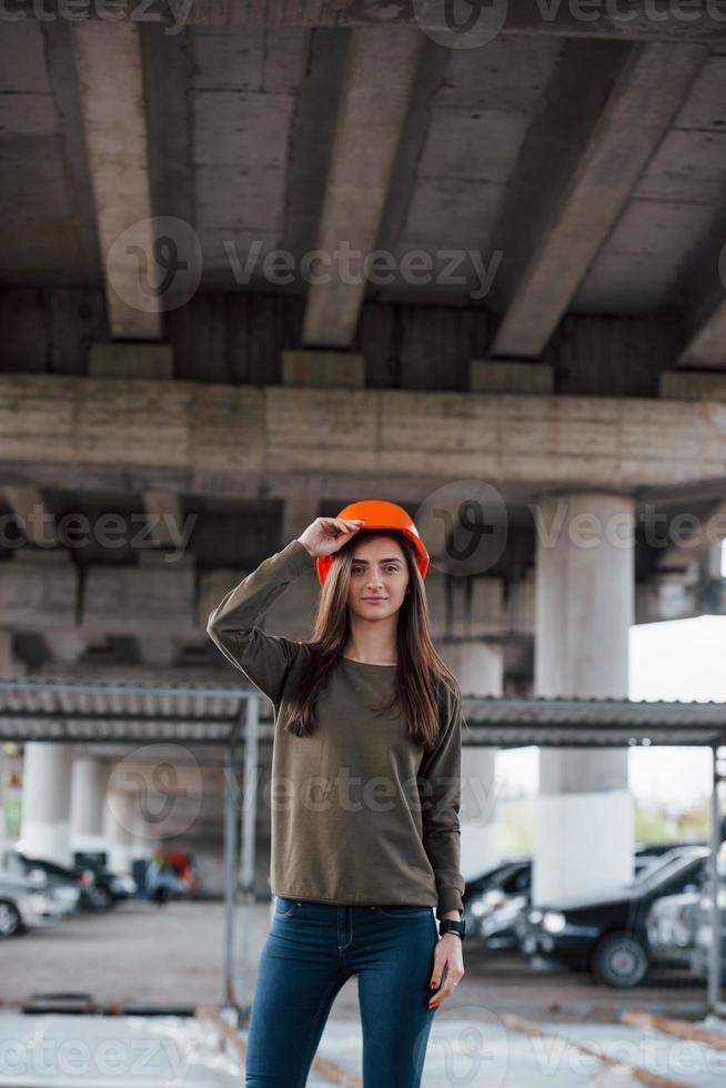Fahrzeug im Hintergrund. Porträt einer schönen jungen Frau mit Schutzhelm, die unter der Brücke steht foto