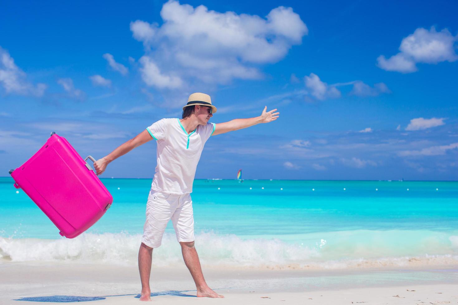 Mann, der mit einem Koffer auf einem Strand geht foto