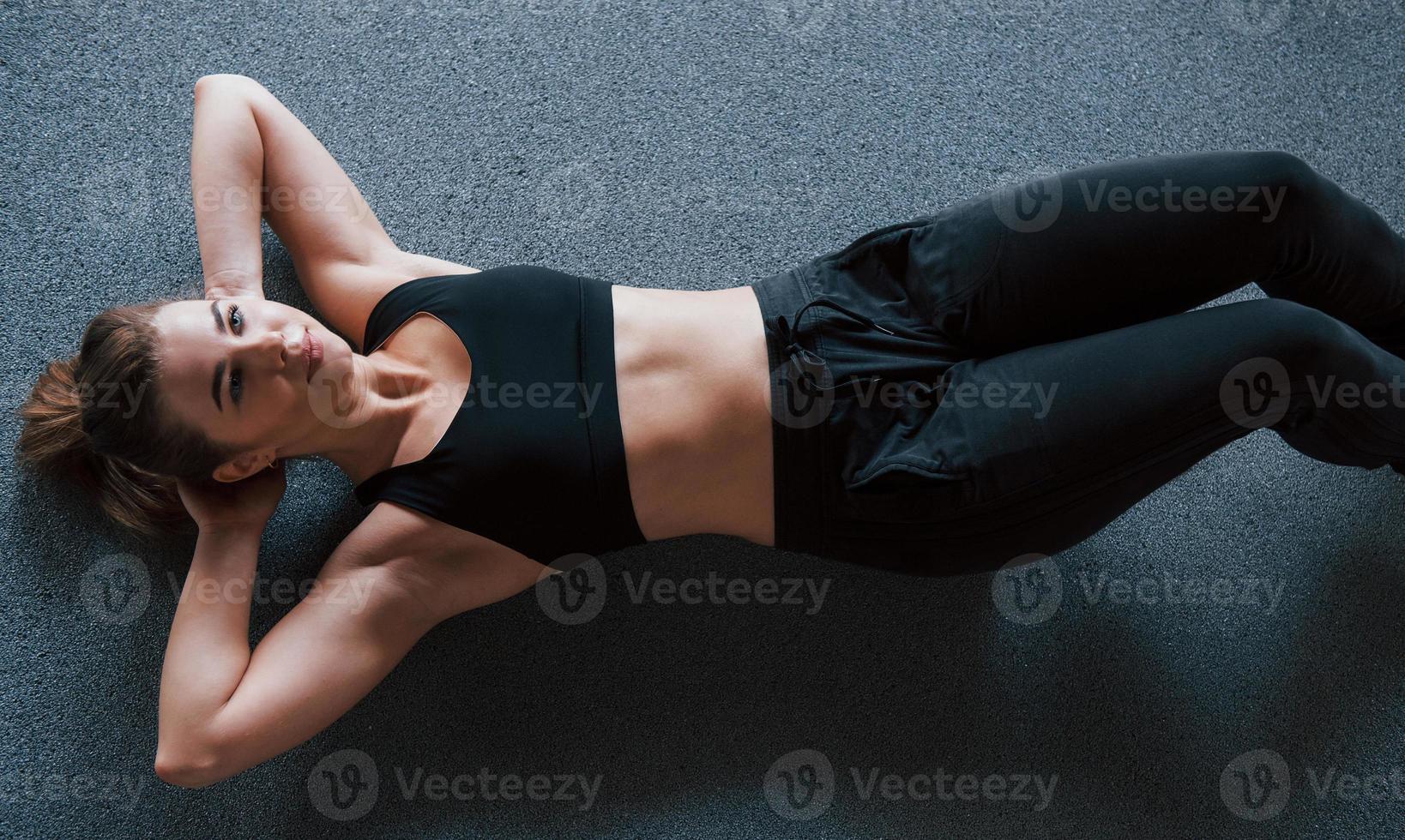 mit sauberer Haut. Bauchmuskeln auf dem Boden im Fitnessstudio machen. schöne weibliche Eignungsfrau foto