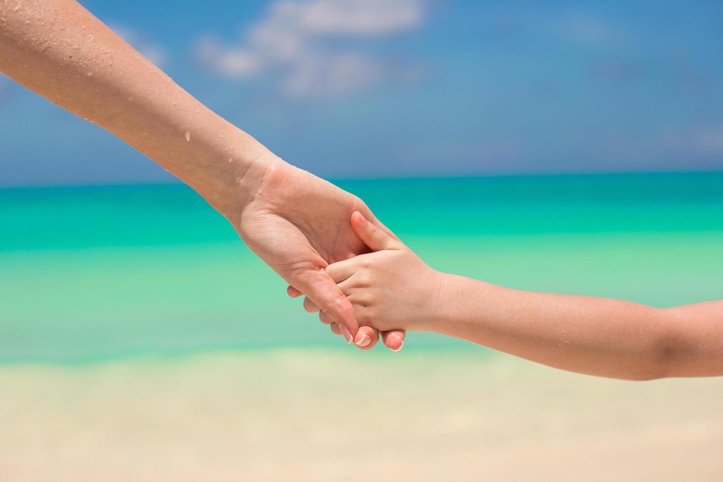 Eltern und Kind, die Hände am Strand halten foto