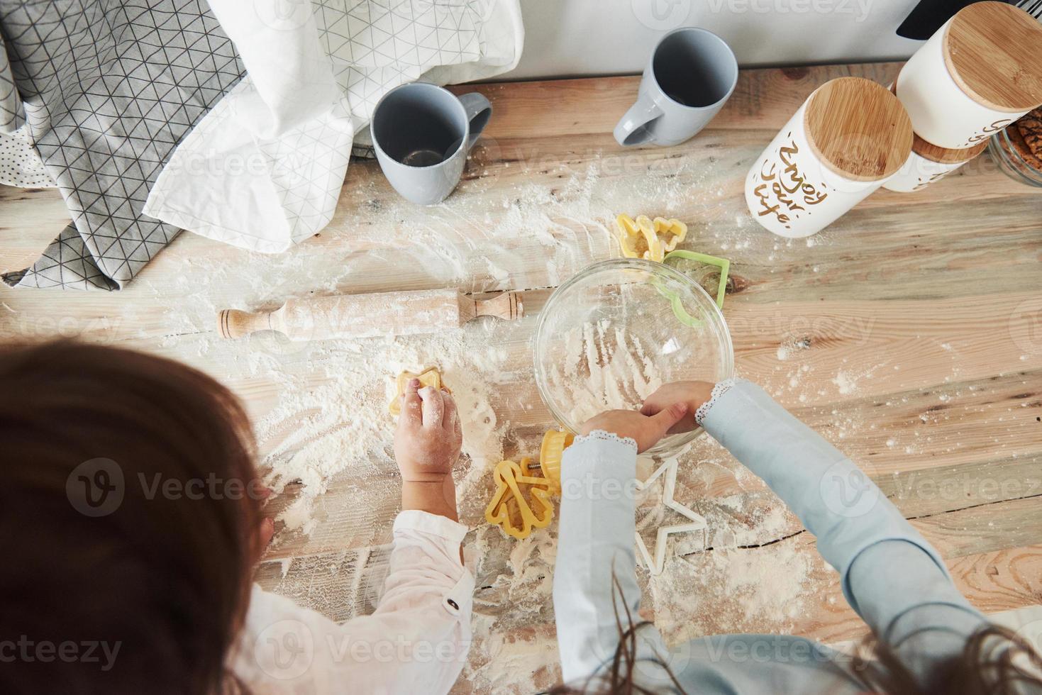 Draufsicht auf Kinder, die lernen, mit speziell geformten Instrumenten Essen aus dem Mehl zuzubereiten foto
