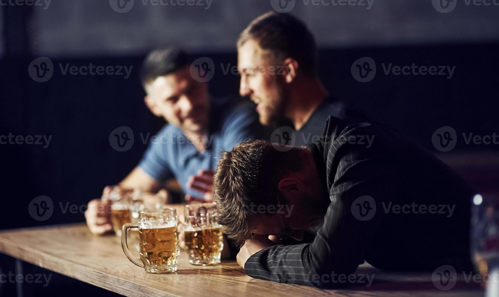 Drei männliche Freunde in der Bar. Unterstützung trauriger Freund. Einheit der Menschen. mit Bier auf dem Tisch foto