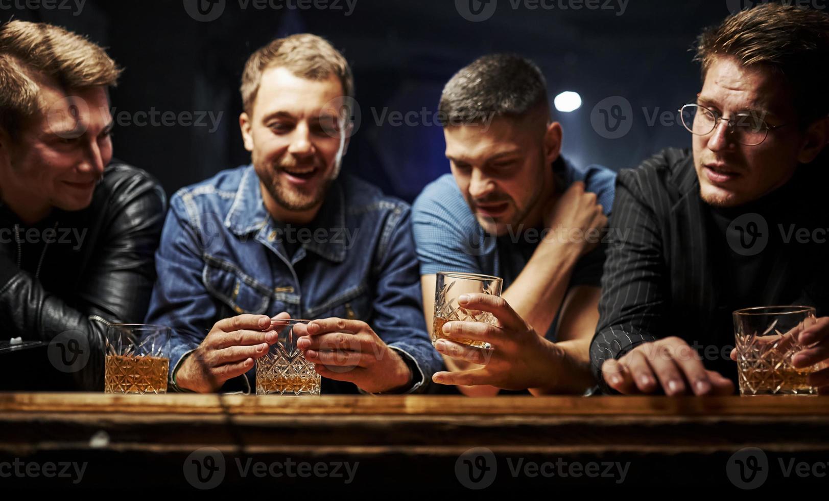 Vorderansicht. freunde ruhen sich mit alkohol in den händen in der kneipe aus. Gespräch haben foto