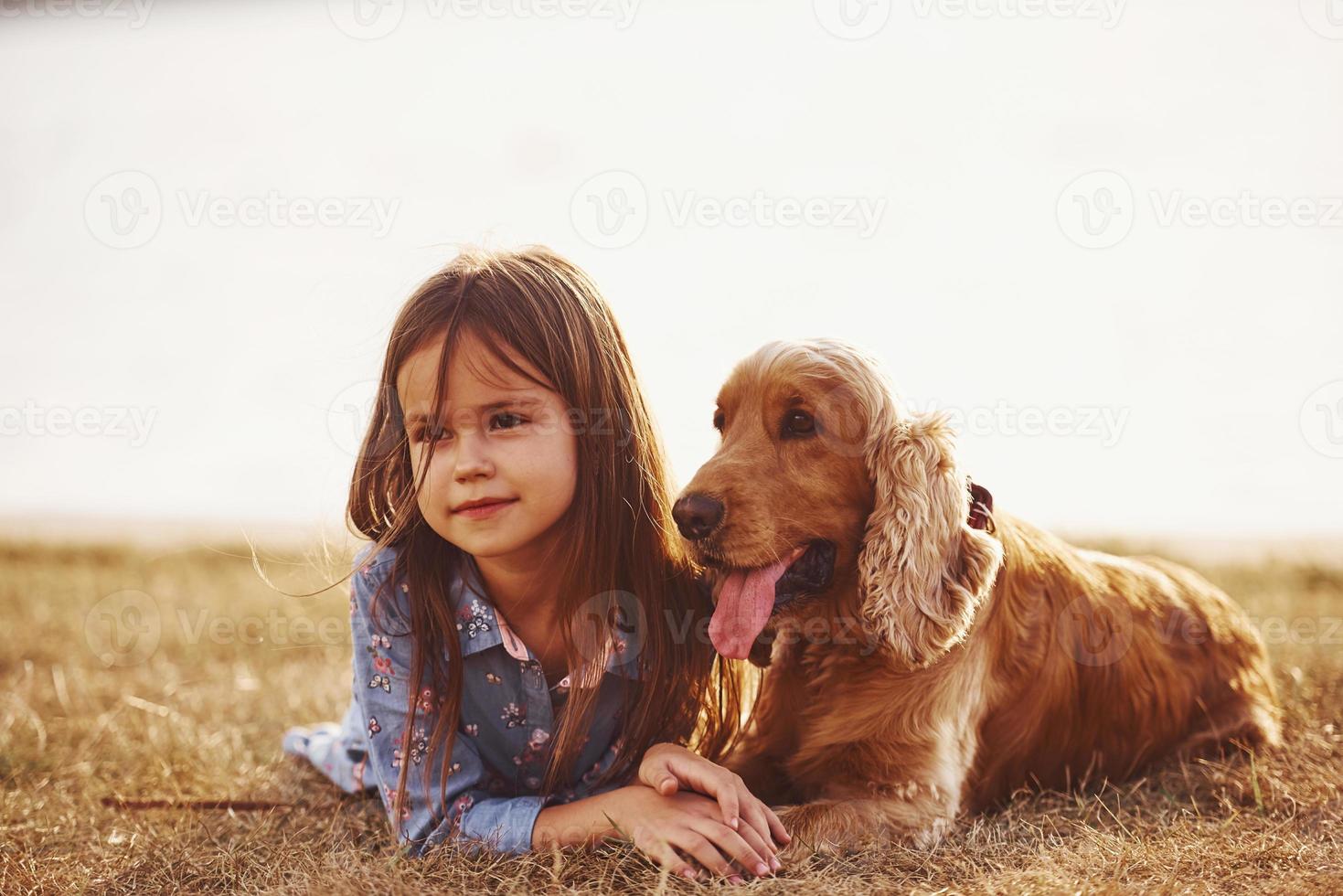 warm und ruhig. süßes kleines Mädchen geht an sonnigen Tagen mit ihrem Hund im Freien spazieren foto