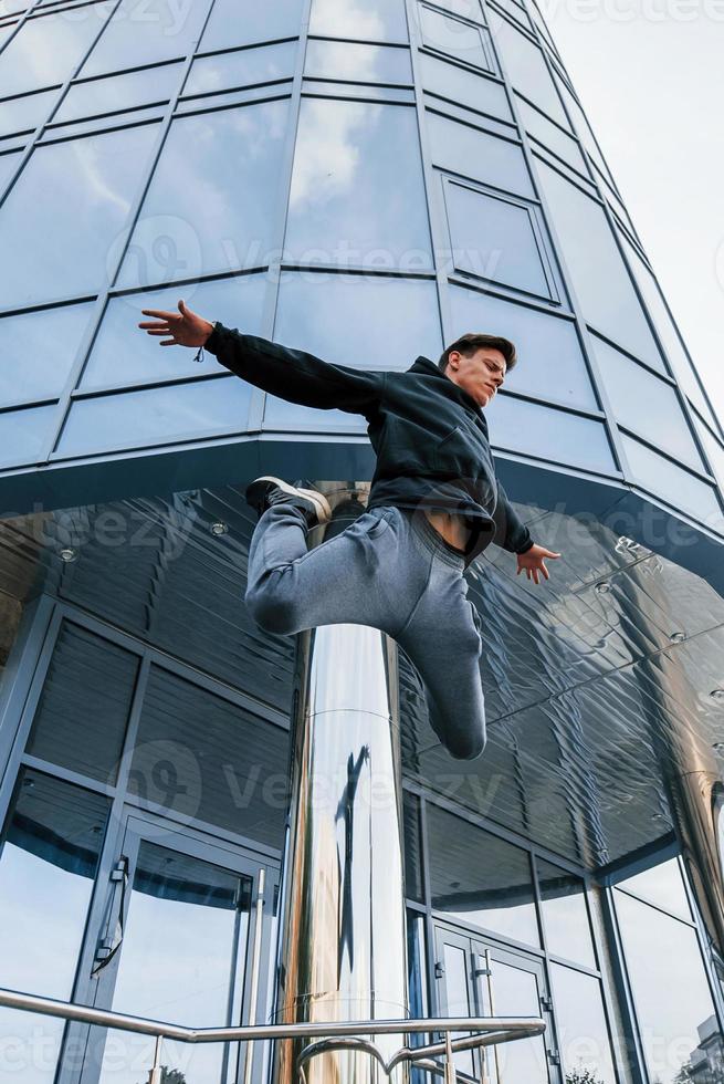 junger Mann, der tagsüber Parkour in der Stadt macht. Konzeption von Extremsportarten foto