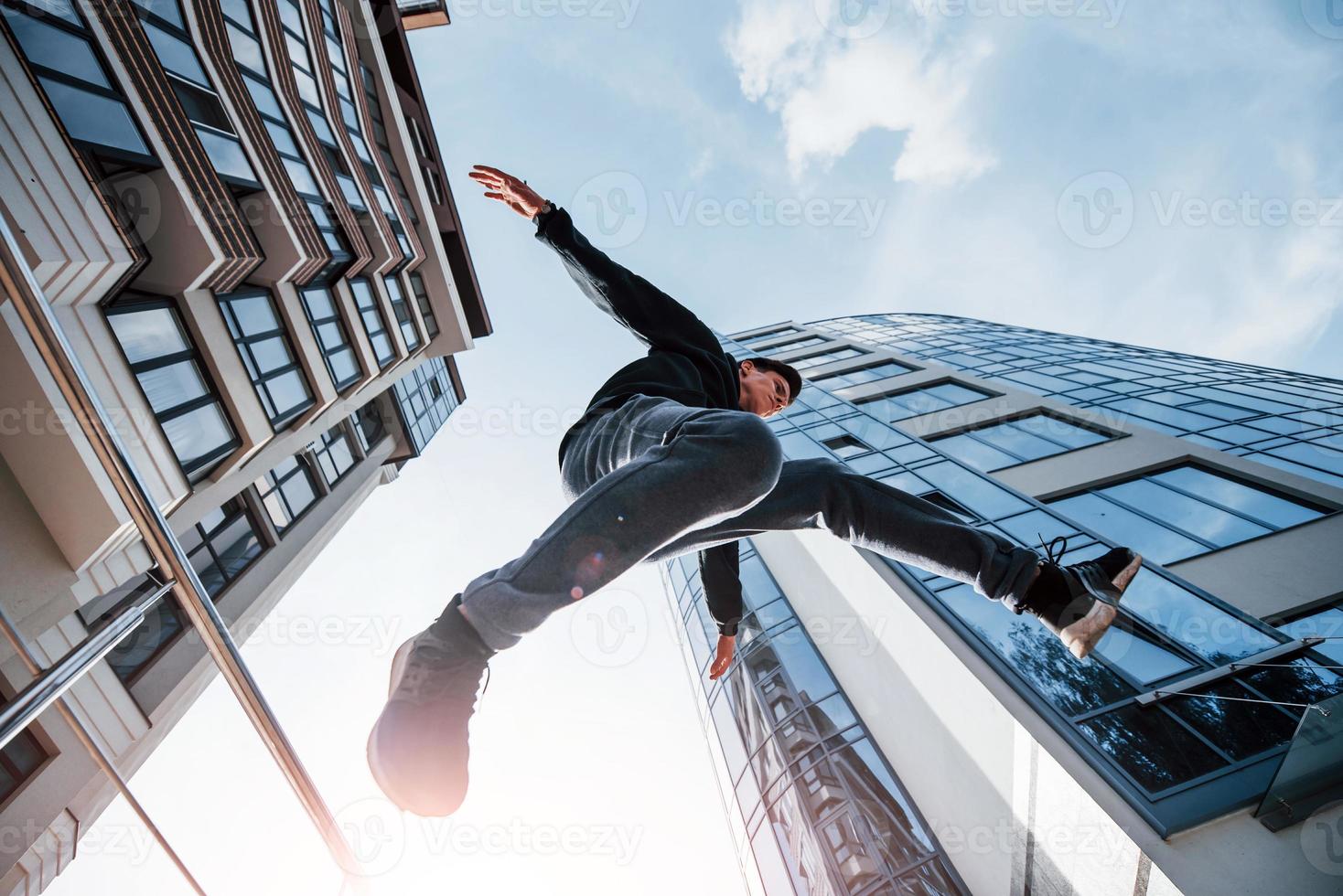 junger Mann, der tagsüber Parkour in der Stadt macht. Konzeption von Extremsportarten foto