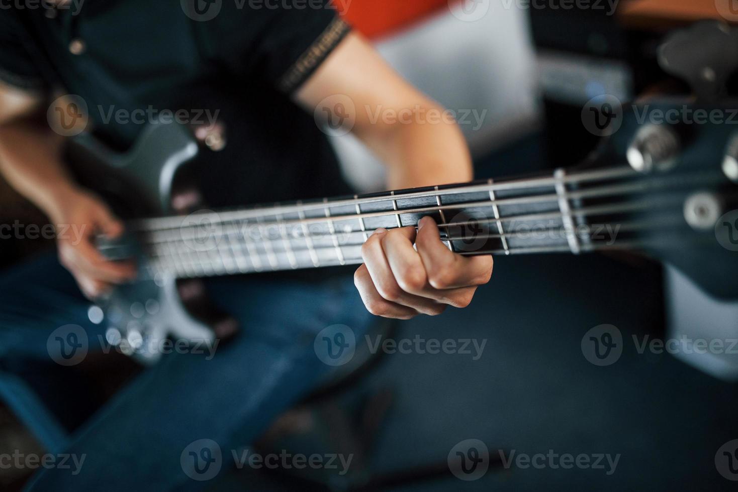 Nahaufnahme des Musikers spielt Bassgitarre im Innenbereich foto