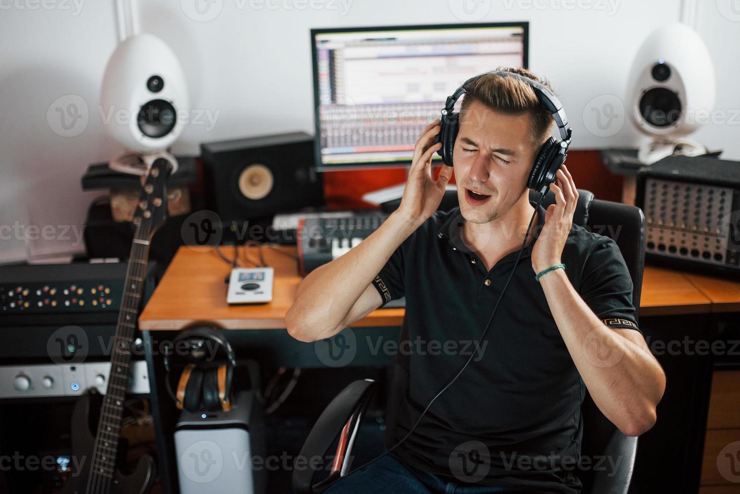 zufrieden mit der Audioqualität. toningenieur mit kopfhörern, der musik drinnen im studio bearbeitet und mischt foto