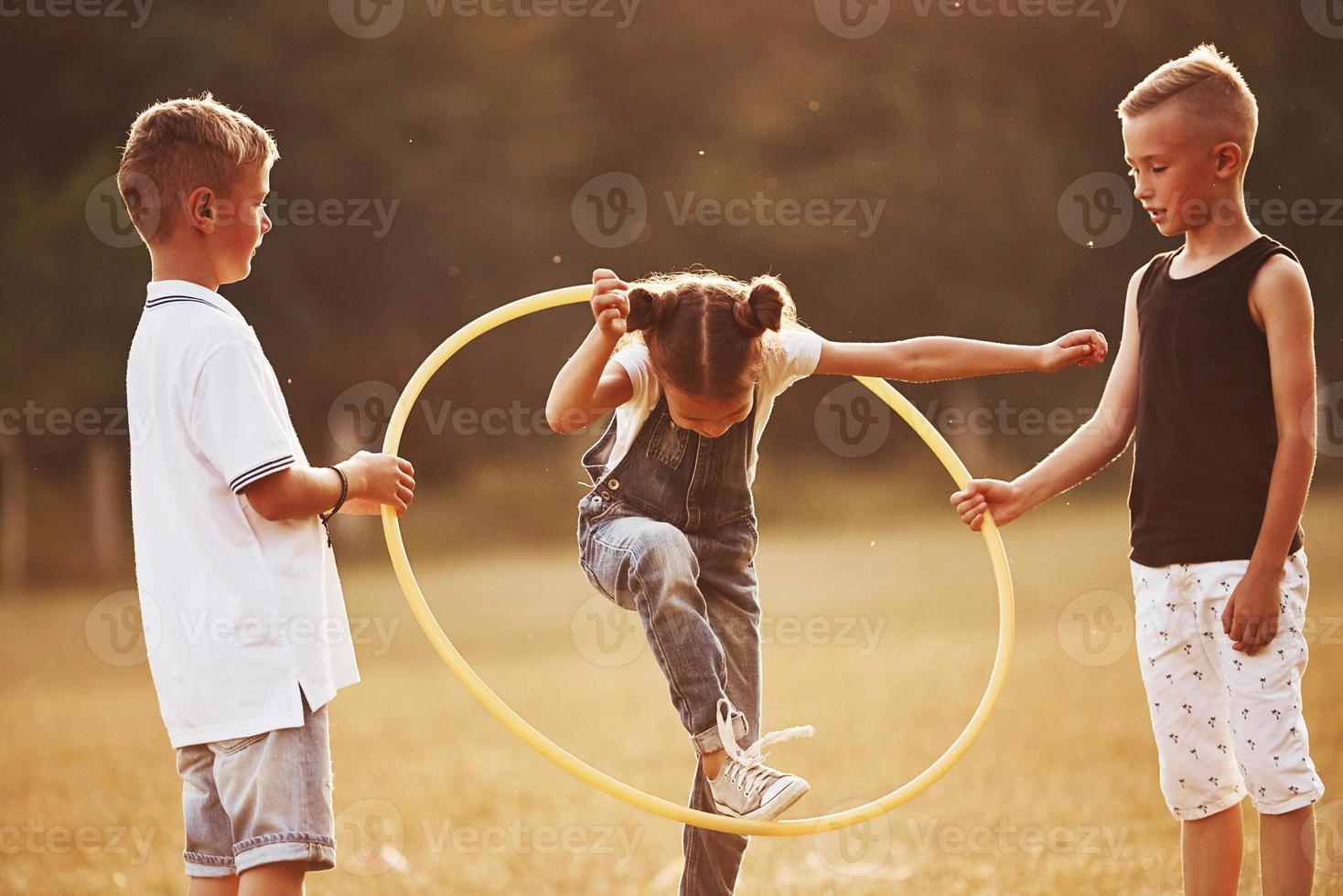 Springen durch das Kreis-Fitness-Tool. kinder haben spaß auf dem feld foto