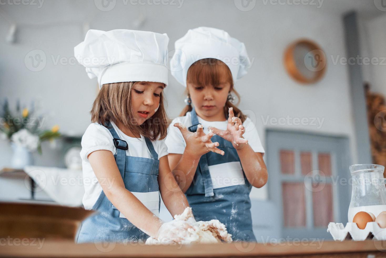 Familienkinder in weißer Kochuniform bereiten Essen in der Küche zu foto