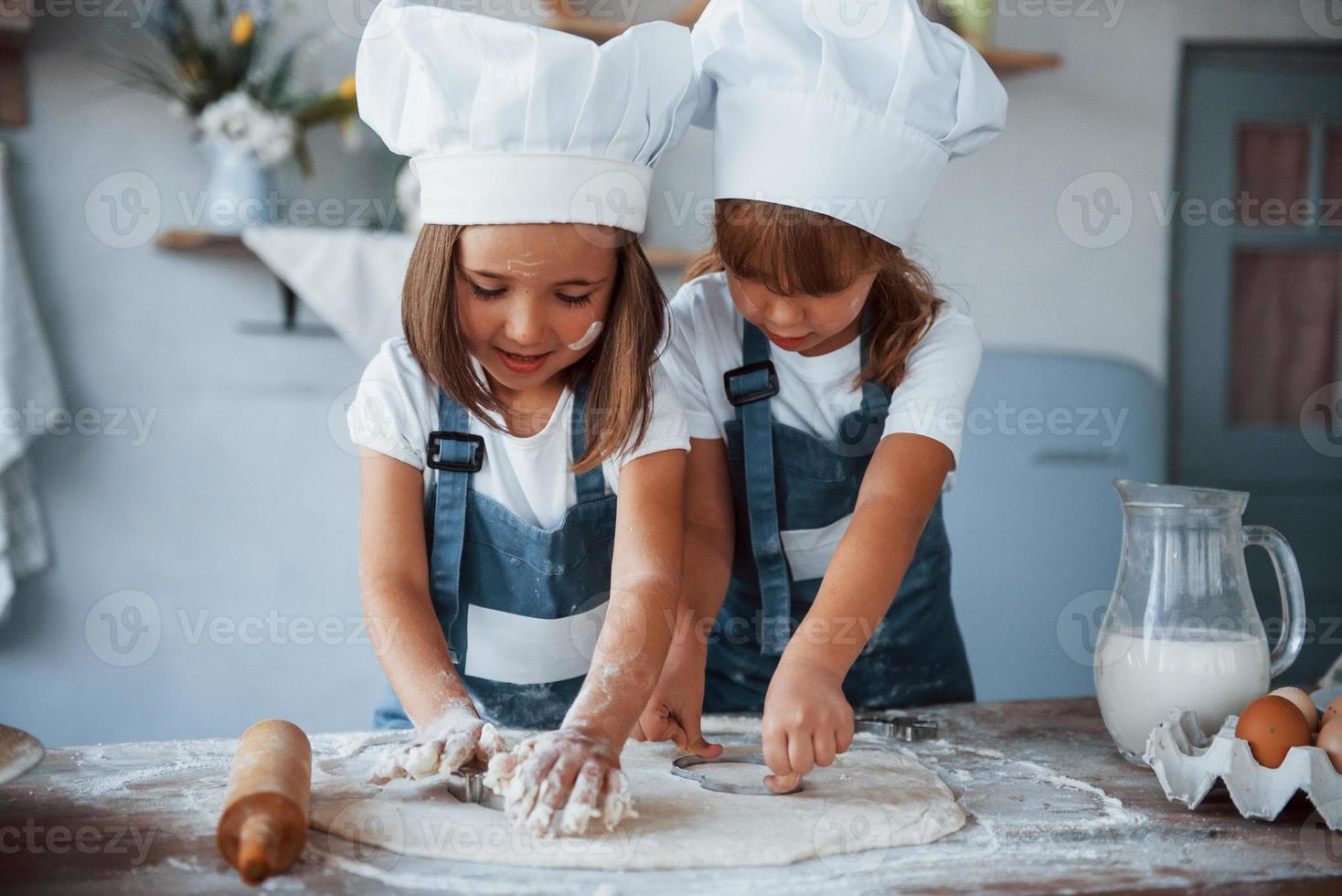 Familienkinder in weißer Kochuniform bereiten Essen in der Küche zu foto