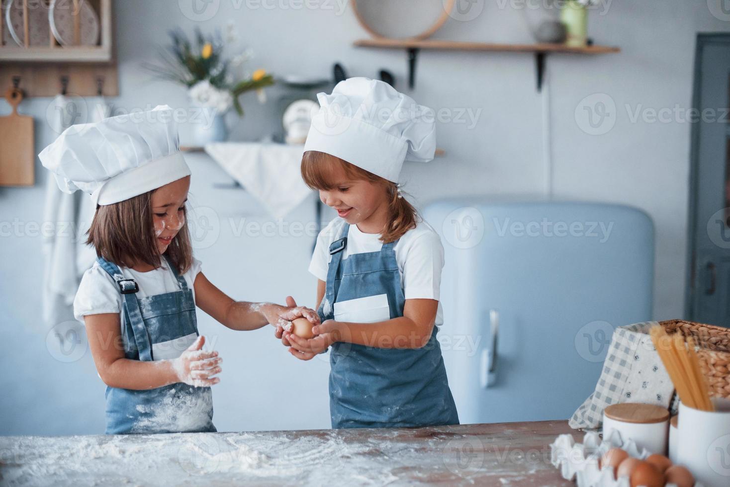 mit Eiern spielen. Familienkinder in weißer Kochuniform bereiten Essen in der Küche zu foto