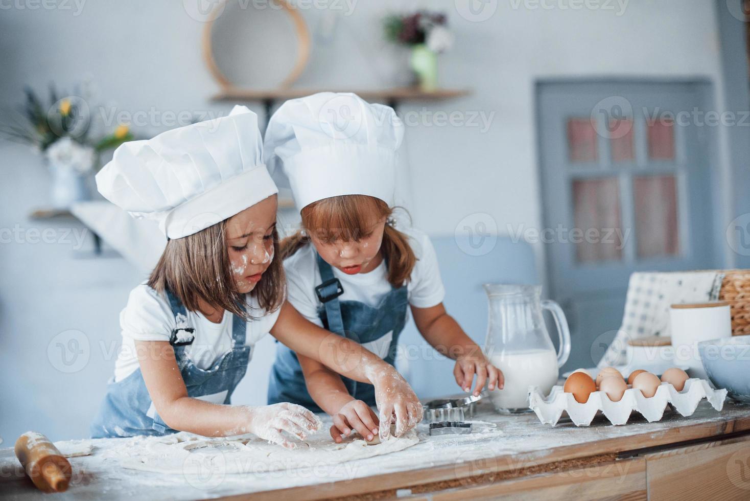 Konzentration aufs Kochen. Familienkinder in weißer Kochuniform bereiten Essen in der Küche zu foto