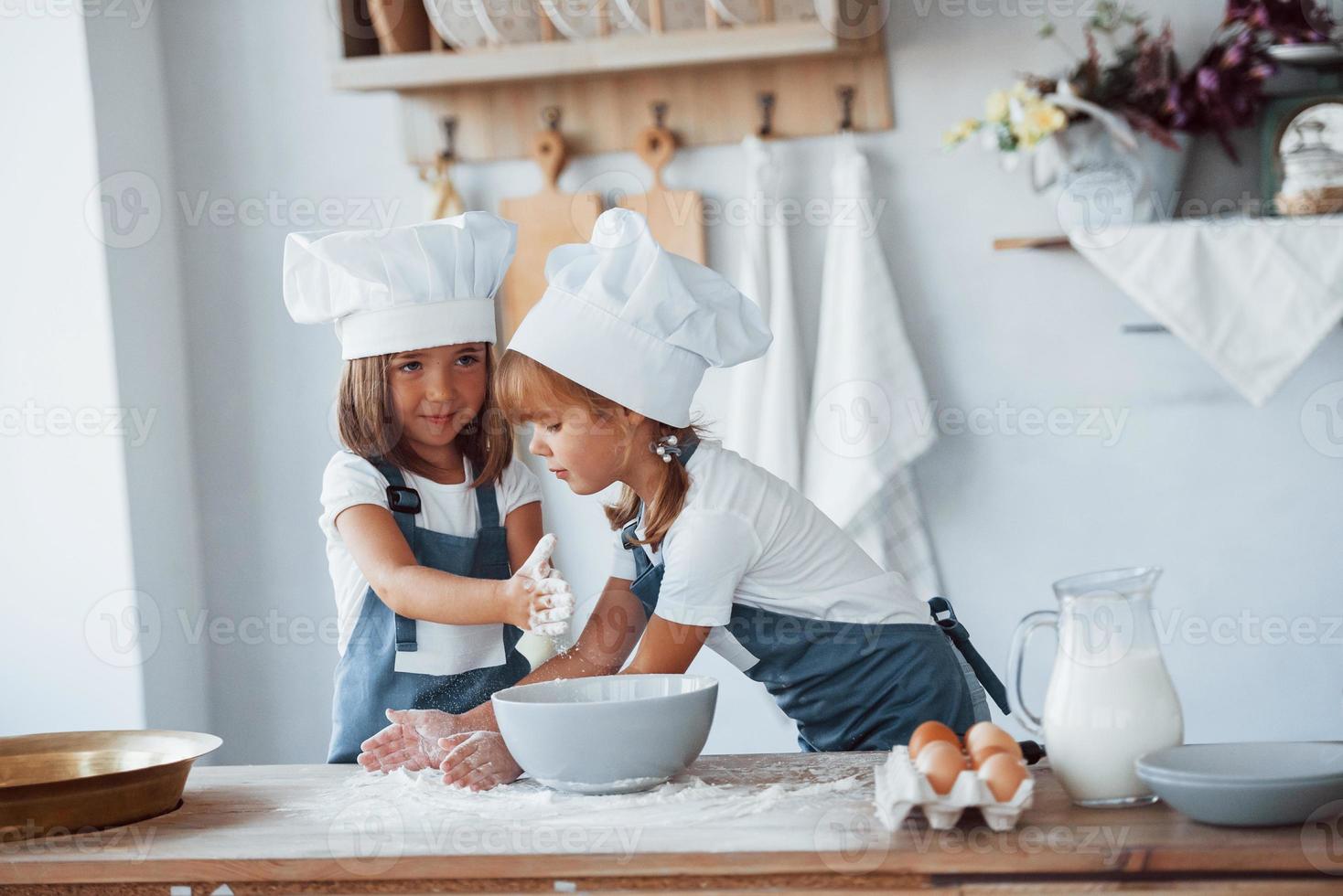 Familienkinder in weißer Kochuniform bereiten Essen in der Küche zu foto