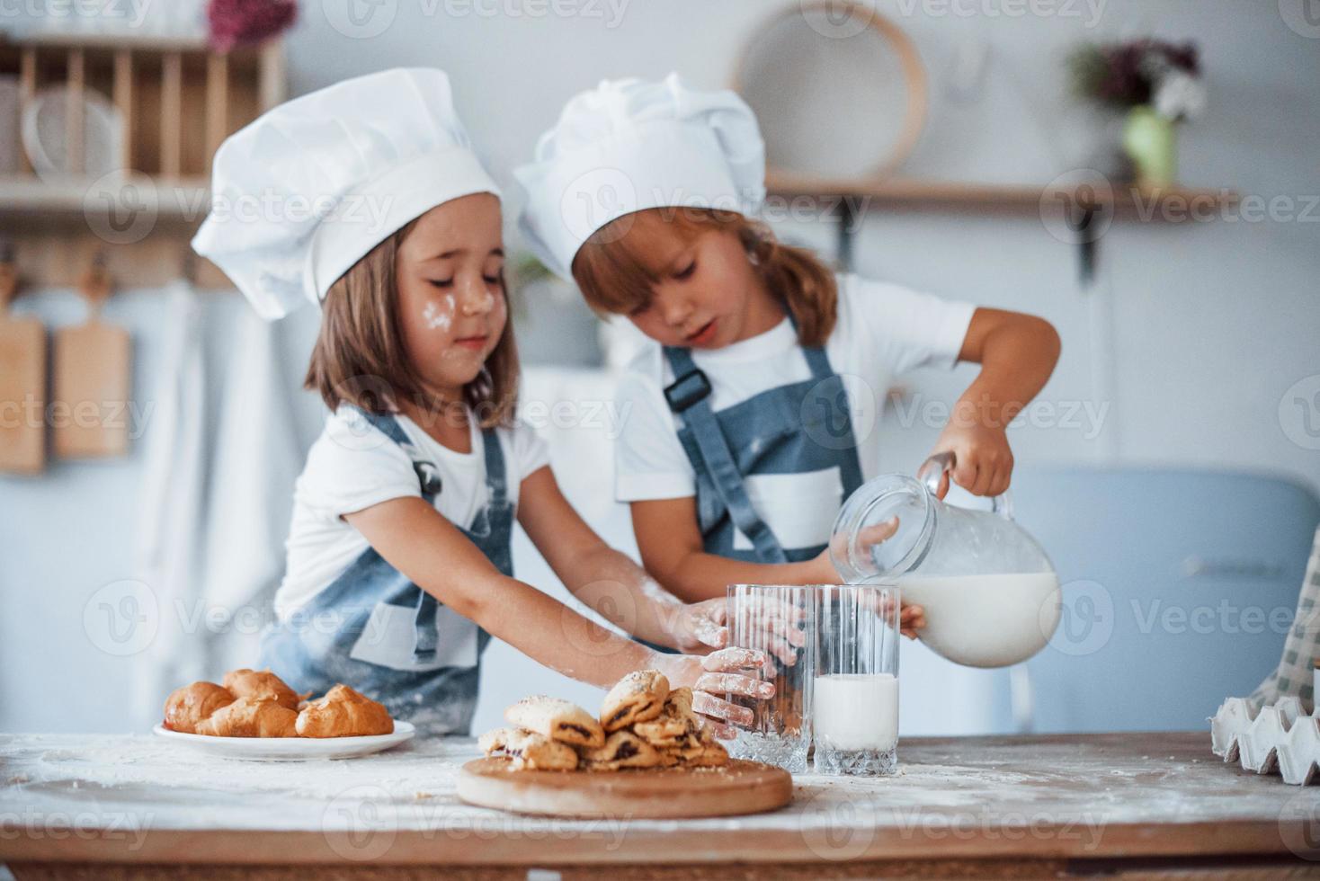 Kekse sind fertig. Familienkinder in weißer Kochuniform bereiten Essen in der Küche zu foto