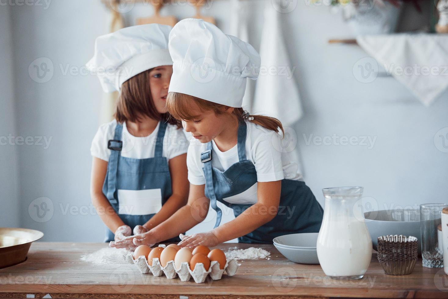 Familienkinder in weißer Kochuniform bereiten Essen in der Küche zu foto