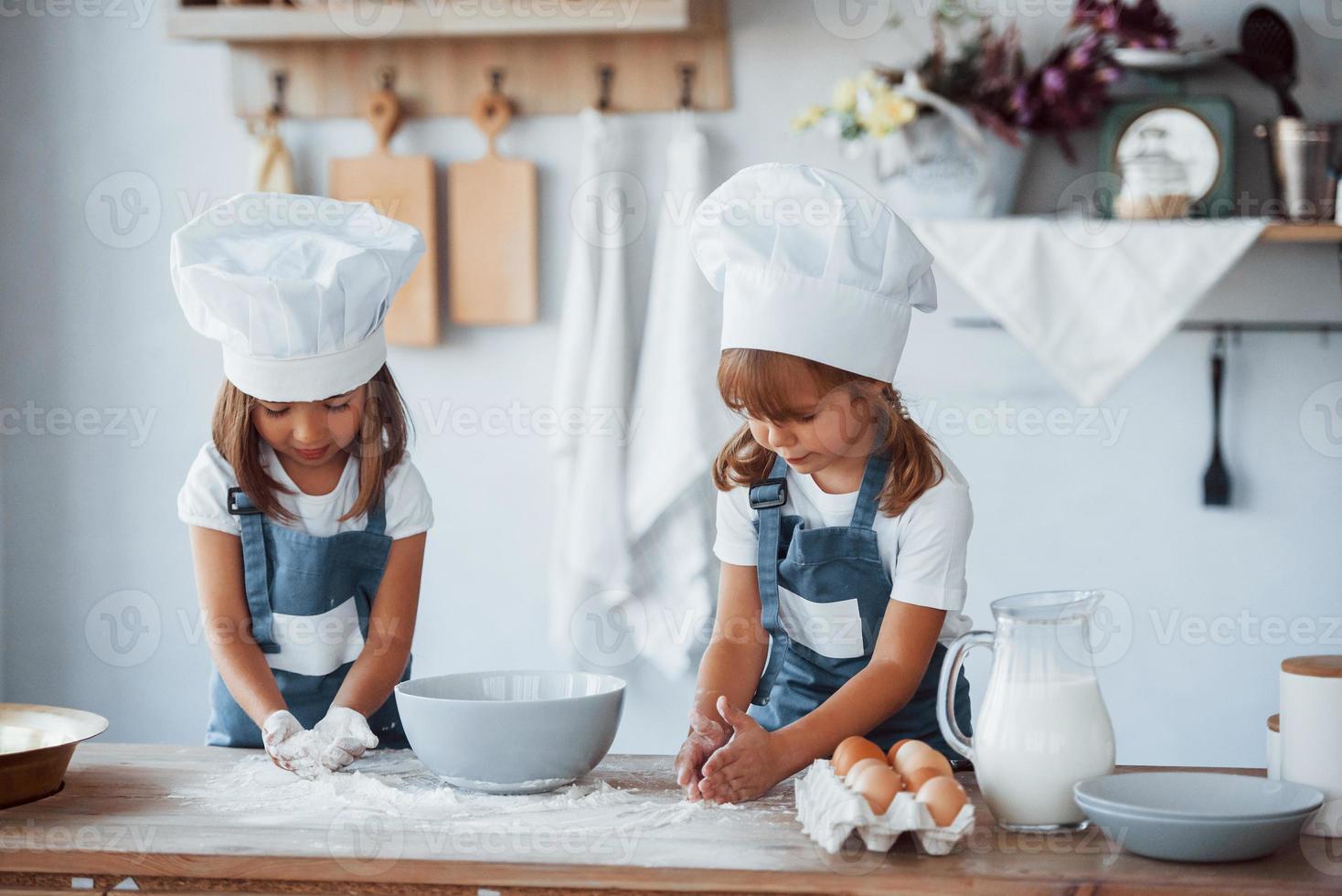 Familienkinder in weißer Kochuniform bereiten Essen in der Küche zu foto