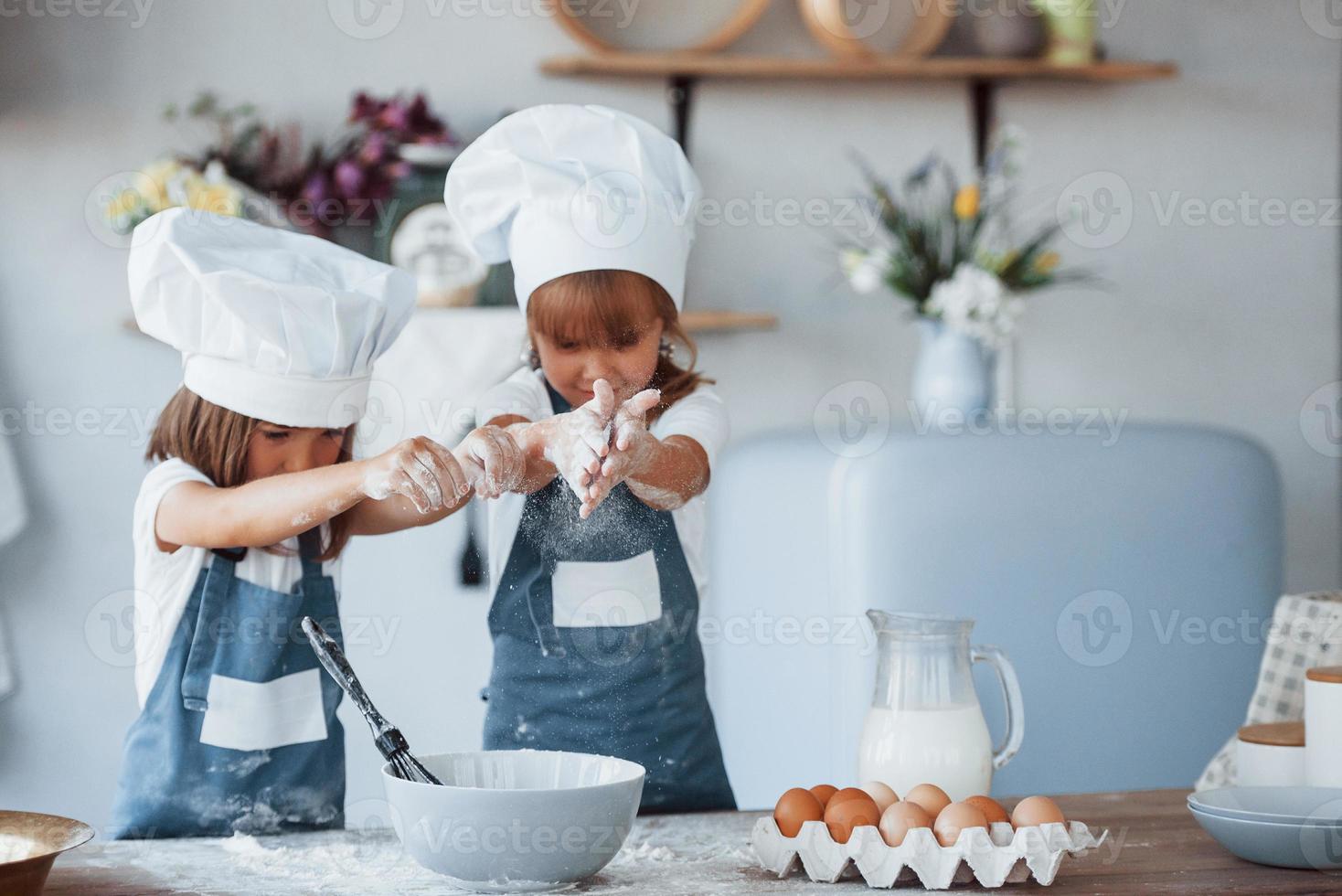 Familienkinder in weißer Kochuniform bereiten Essen in der Küche zu foto