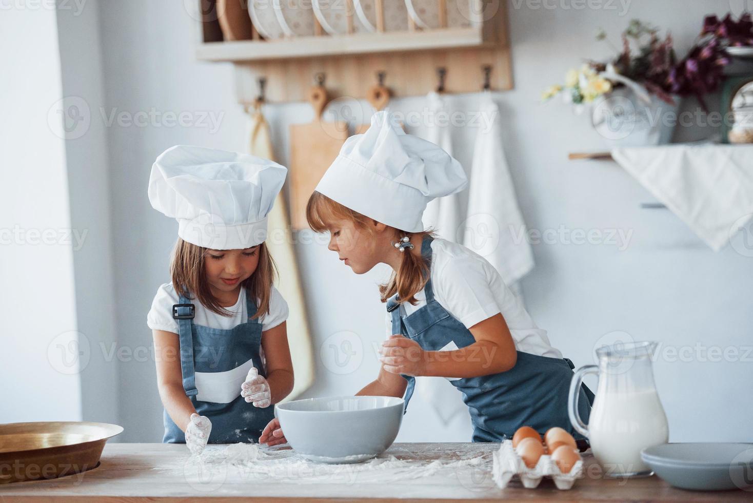 Familienkinder in weißer Kochuniform bereiten Essen in der Küche zu foto