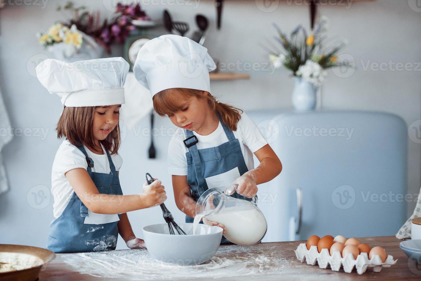 Familienkinder in weißer Kochuniform bereiten Essen in der Küche zu foto