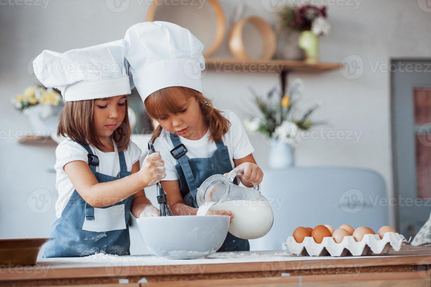 Familienkinder in weißer Kochuniform bereiten Essen in der Küche zu foto