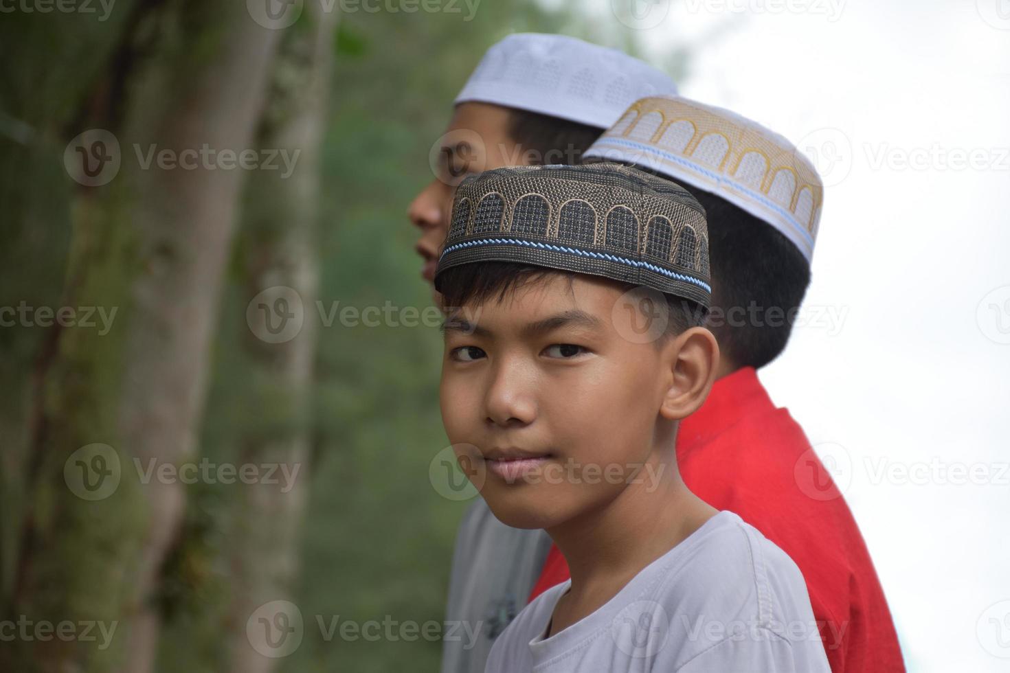Porträt asiatischer muslimischer oder islamischer Jungen, die zusammen vor einem Baum stehen und darauf warten, die religiöse Aktivität in der Schule zu machen, weicher und selektiver Fokus. foto