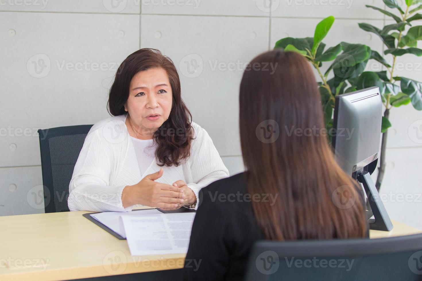 asiatische frau sitzt auf stuhl, während vorstellungsgespräch mit geschäftsführer im büroraum. foto