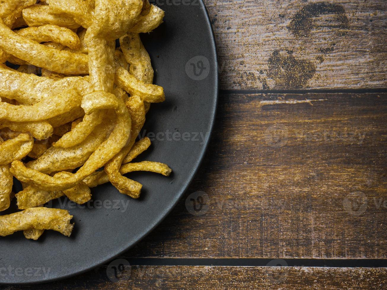 Schweineschwarte in schwarzer Platte auf Holztisch für Food-Konzept foto