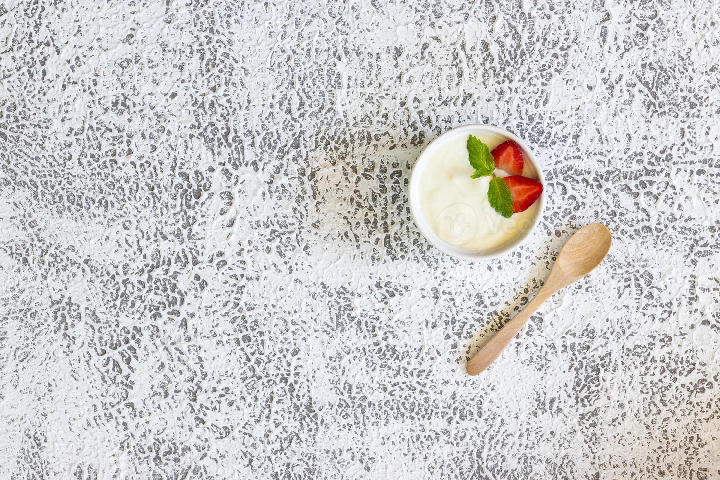 Draufsicht auf Erdbeerjoghurt in einer Holzschale mit Minze und frischen Erdbeeren auf Holzhintergrund. Konzept für gesunde Ernährung. foto