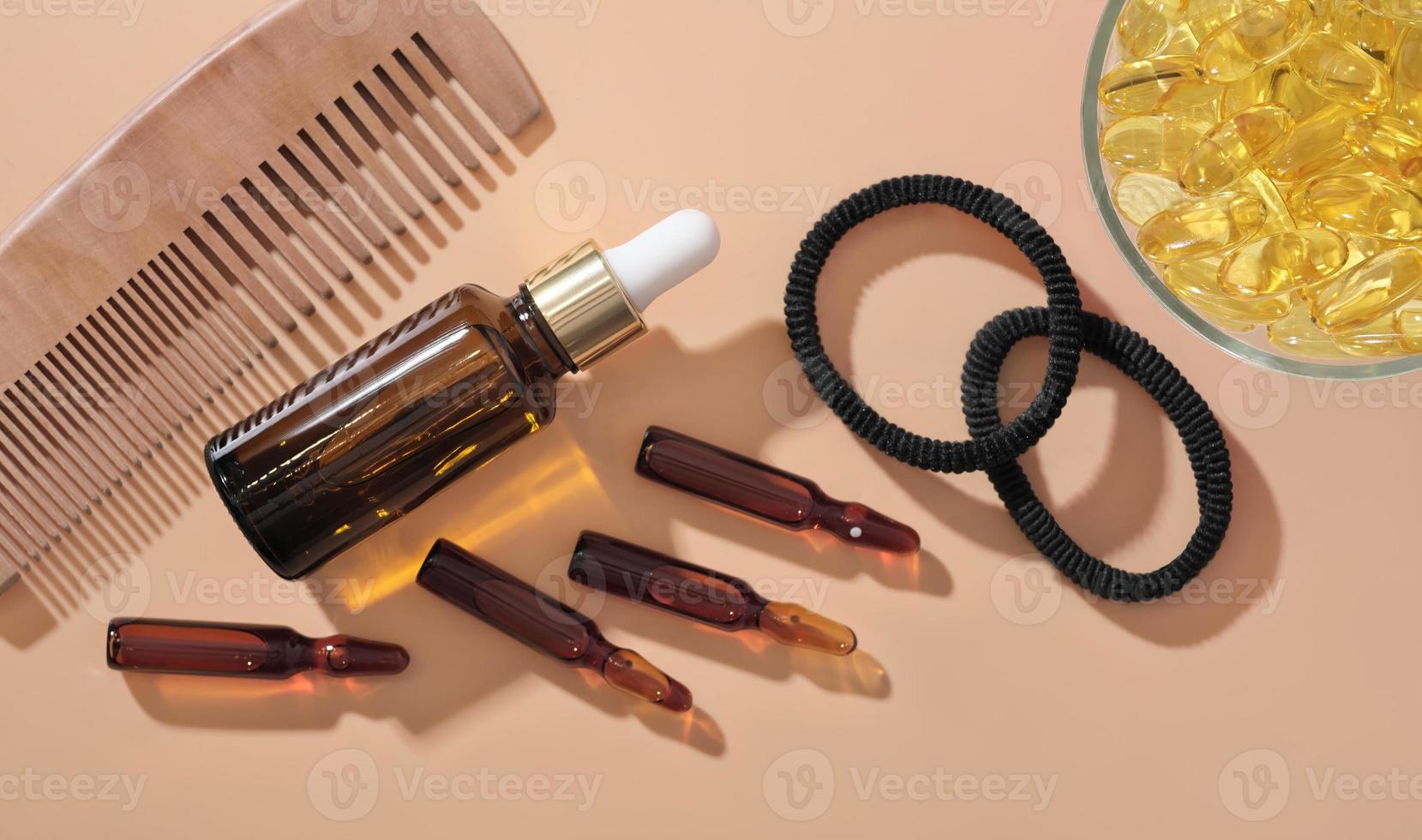 Haarwuchsampullen und Serumlösung neben Omega-3-Kapseln und Holzkamm auf beigem Hintergrund. Haarpflege medizinische Behandlung. Ansicht von oben foto