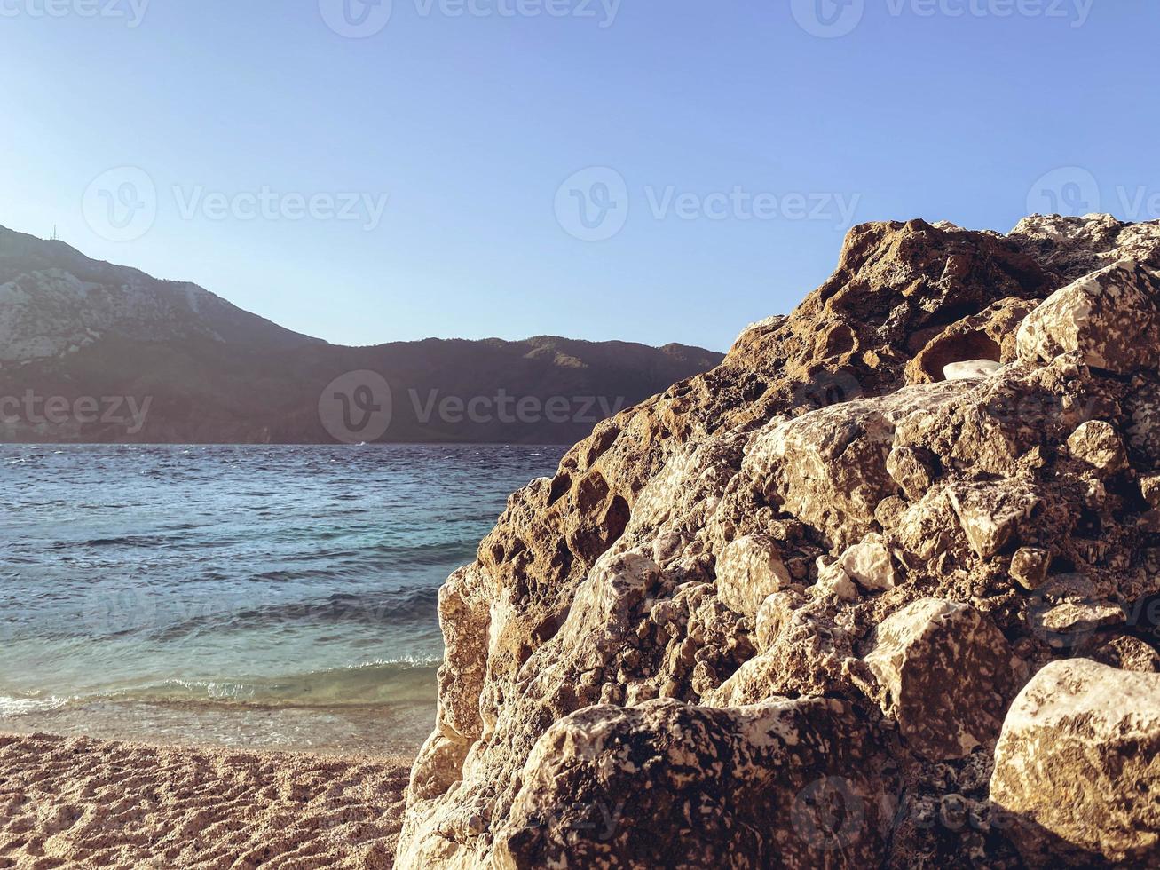 riesige Steine liegen am Strand in der Nähe des Meeres. Sandblock, Felsen. ein stein liegt am meer neben dem sand für einen spaziergang am strand entlang foto