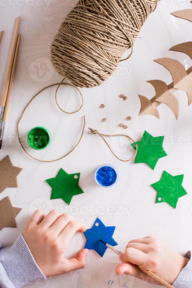 ein kind malt einen gouachestern aus karton für diy weihnachtsdeko. Ansicht von oben und vertikal. foto