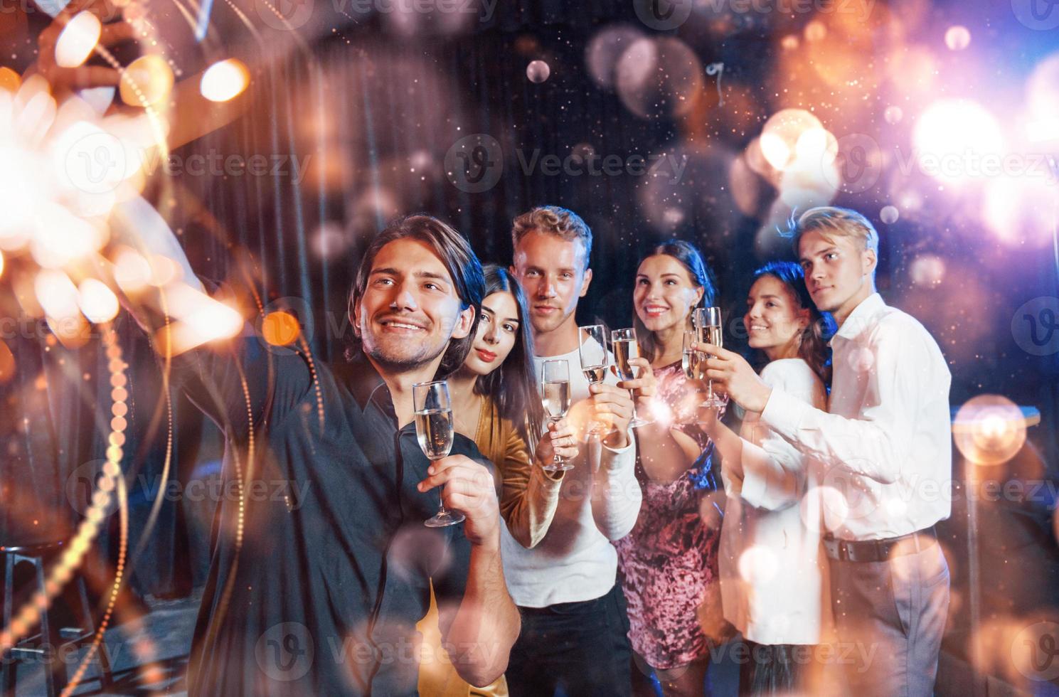 eine gruppe fröhlicher junger leute feiern und feiern das neue jahr drinnen foto