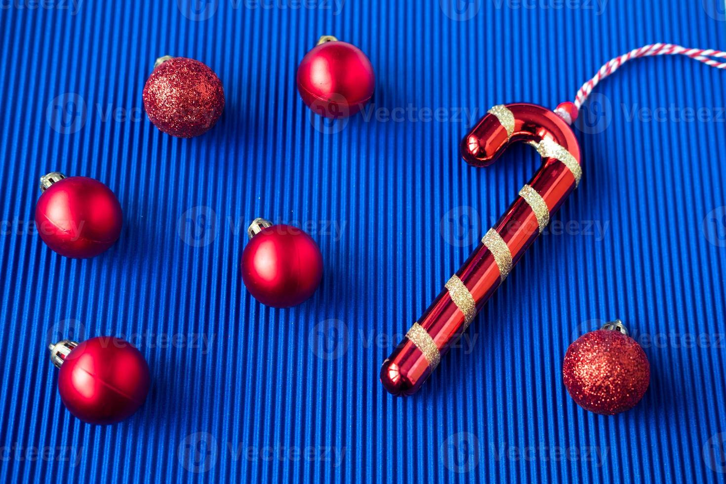 weihnachtsspielzeug in form einer roten kugel und eines roten lutschers in form eines hakens auf blauem hintergrund. foto