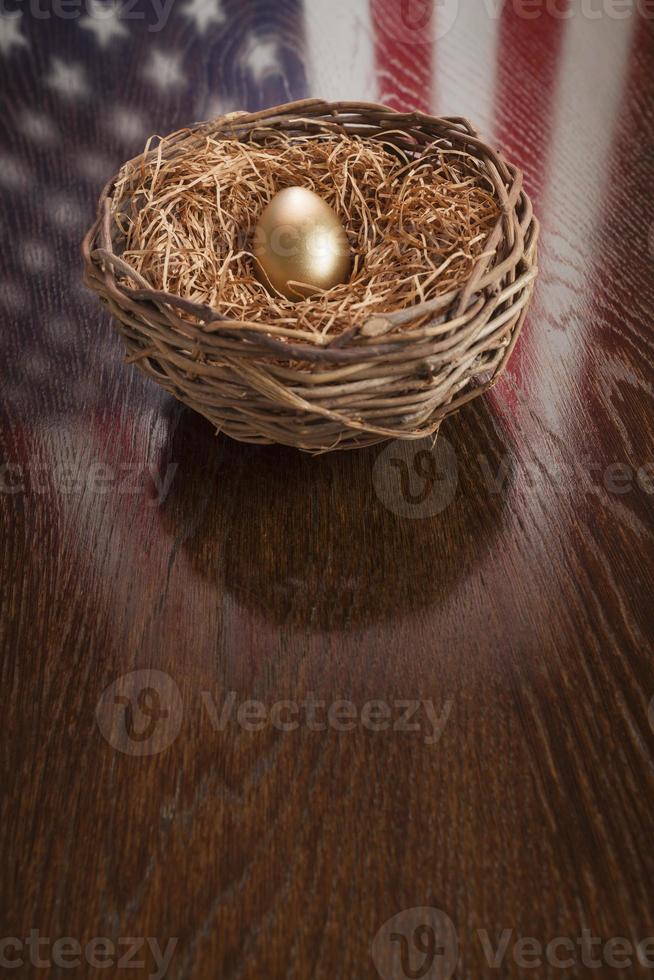 Goldenes Ei im Nest mit Reflexion der amerikanischen Flagge auf dem Tisch foto