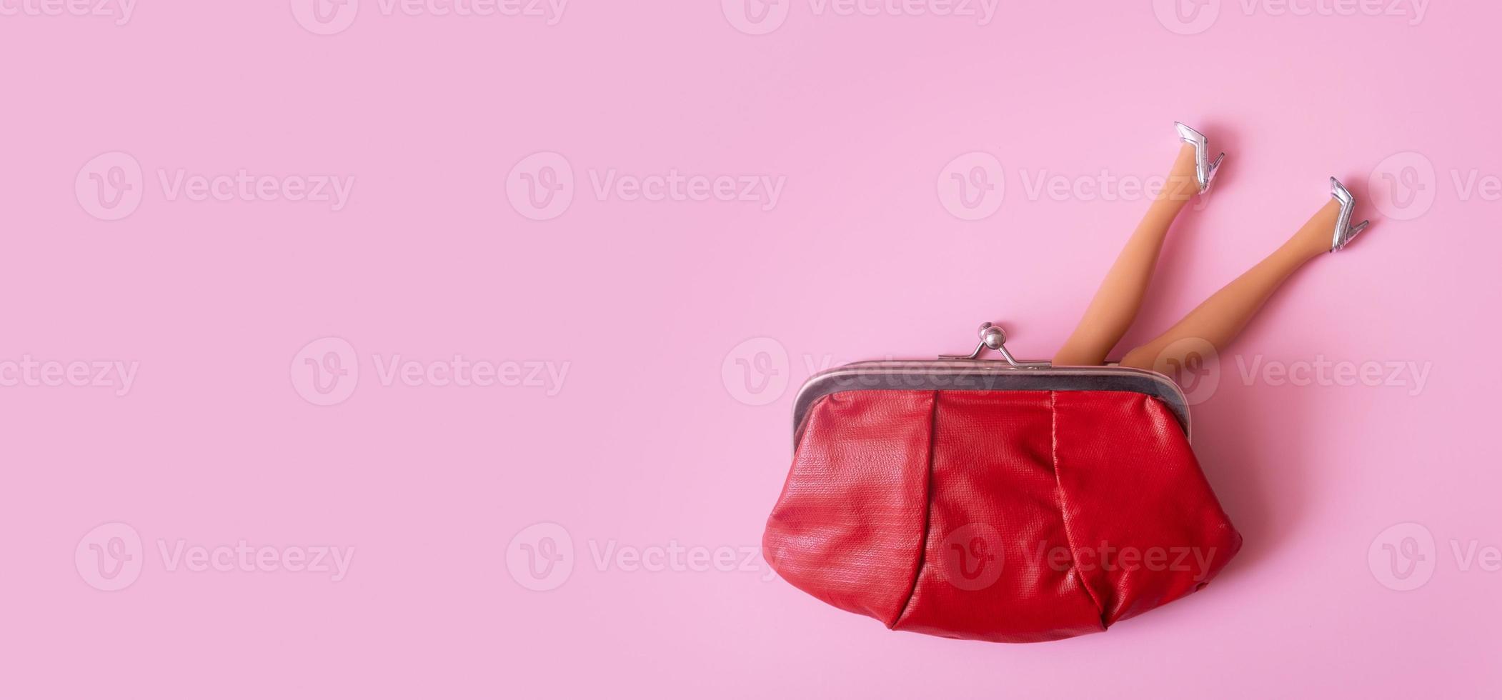 Puppenbeine in silbernen Schuhen, die aus der Draufsicht der Brieftasche herausragen. kreatives weibliches einkaufs- oder finanzkonzept foto