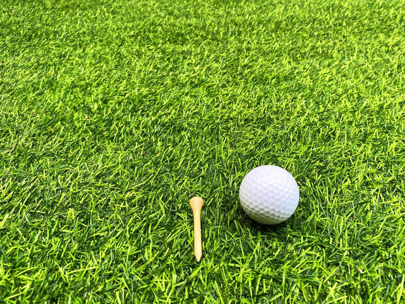 golfball nah oben auf grünem gras auf unscharfer schöner landschaft des golfhintergrundes.konzept internationaler sport, der auf präzisionsfähigkeiten zur gesundheitsentspannung angewiesen ist. foto