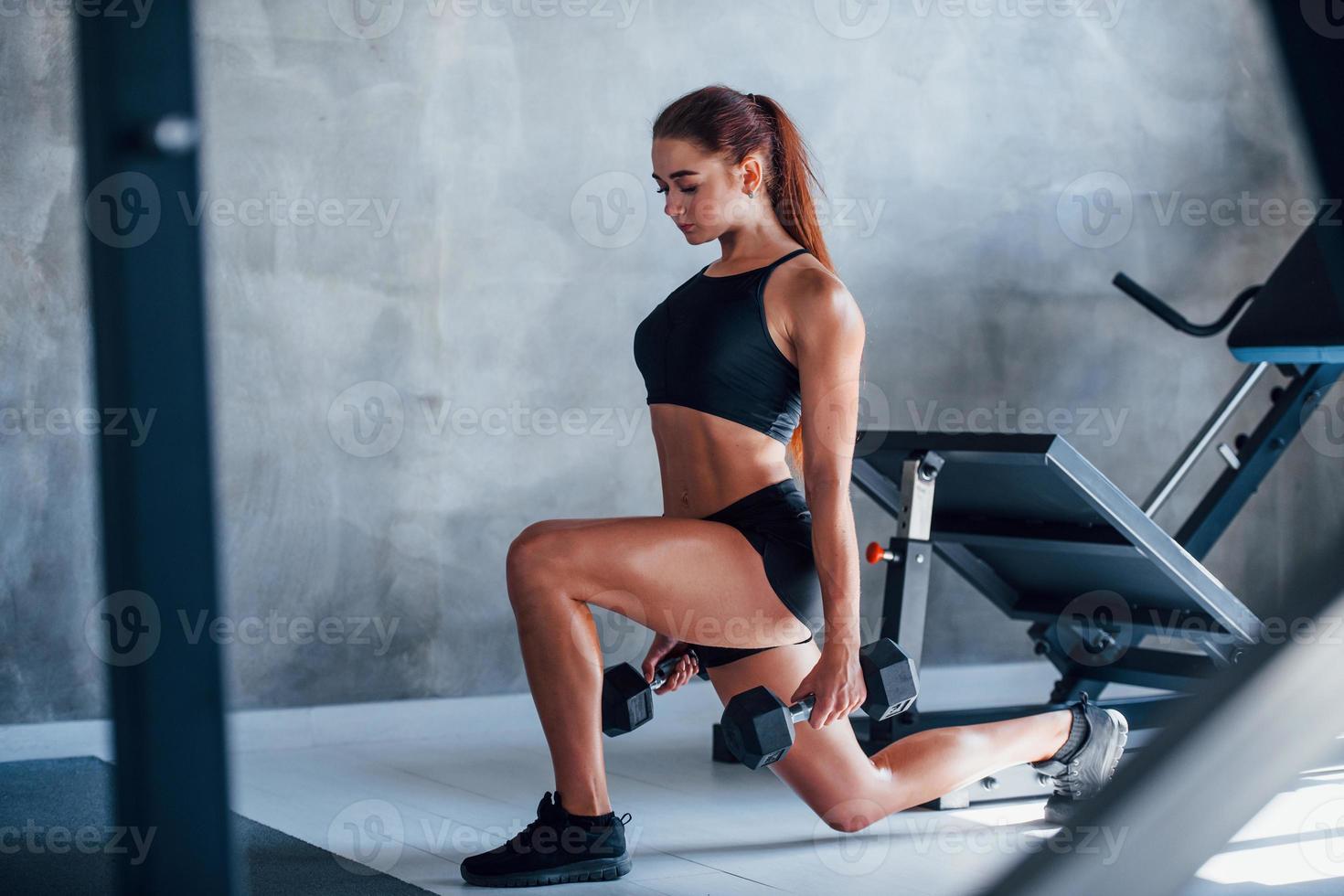 junge fitnessfrau mit schlankem körper und in schwarzer sportlicher kleidung ist im fitnessstudio foto