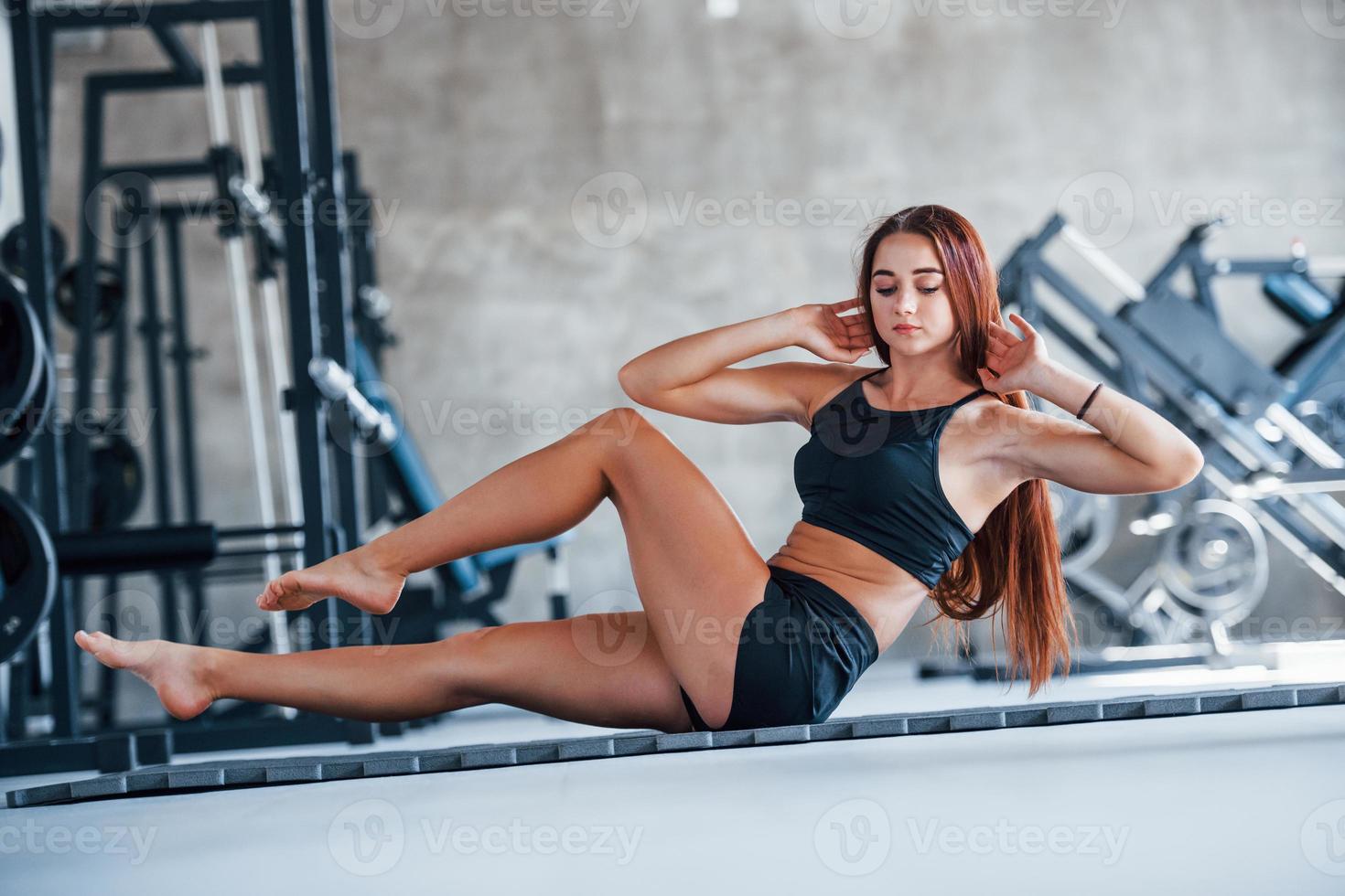 junges fitnessmädchen in schwarzer sportlicher kleidung, das yogaübungen im fitnessstudio macht foto