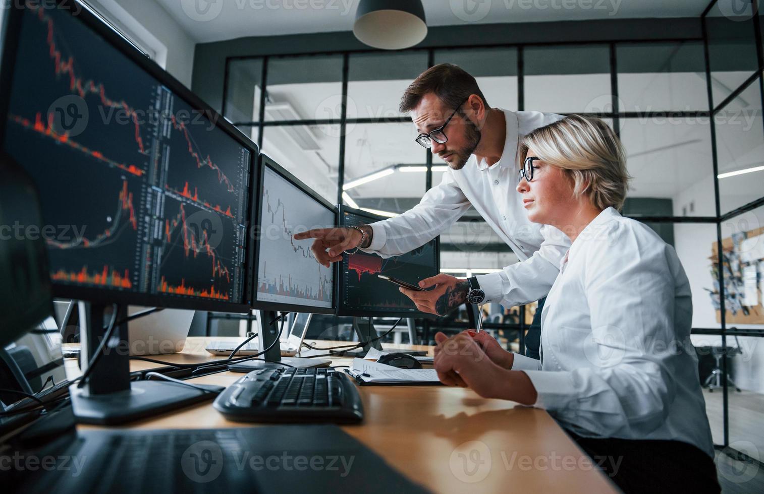 Informationen gemeinsam analysieren. zwei börsenmakler in formeller kleidung arbeiten im büro mit finanzmarkt foto