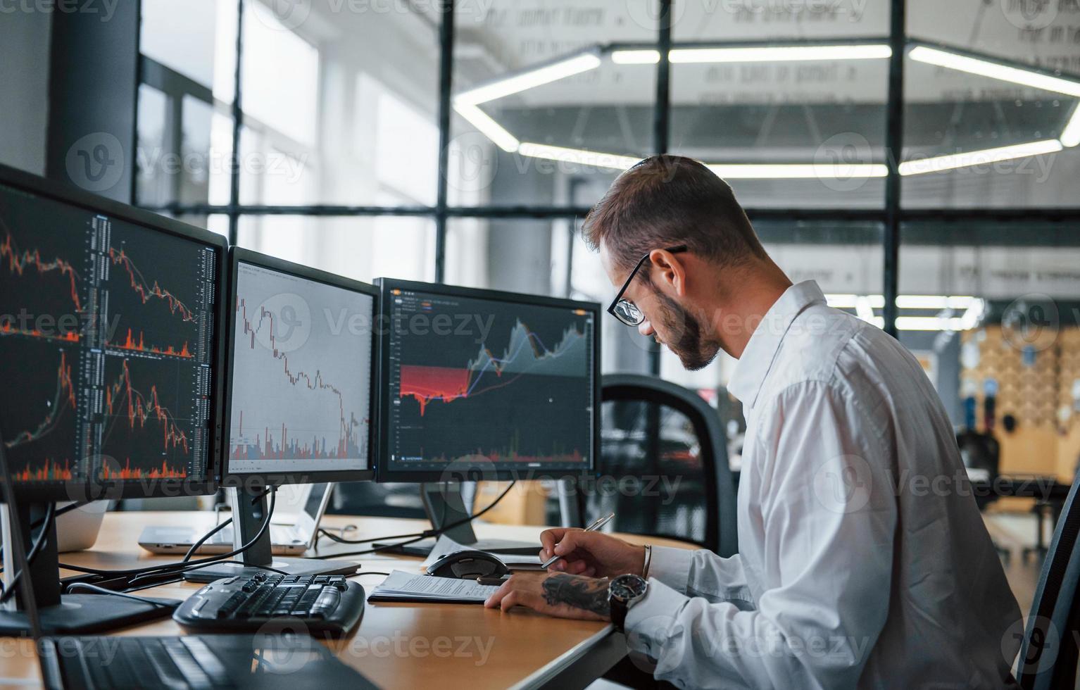 männlicher börsenmakler in formeller kleidung arbeitet im büro mit finanzmarkt foto