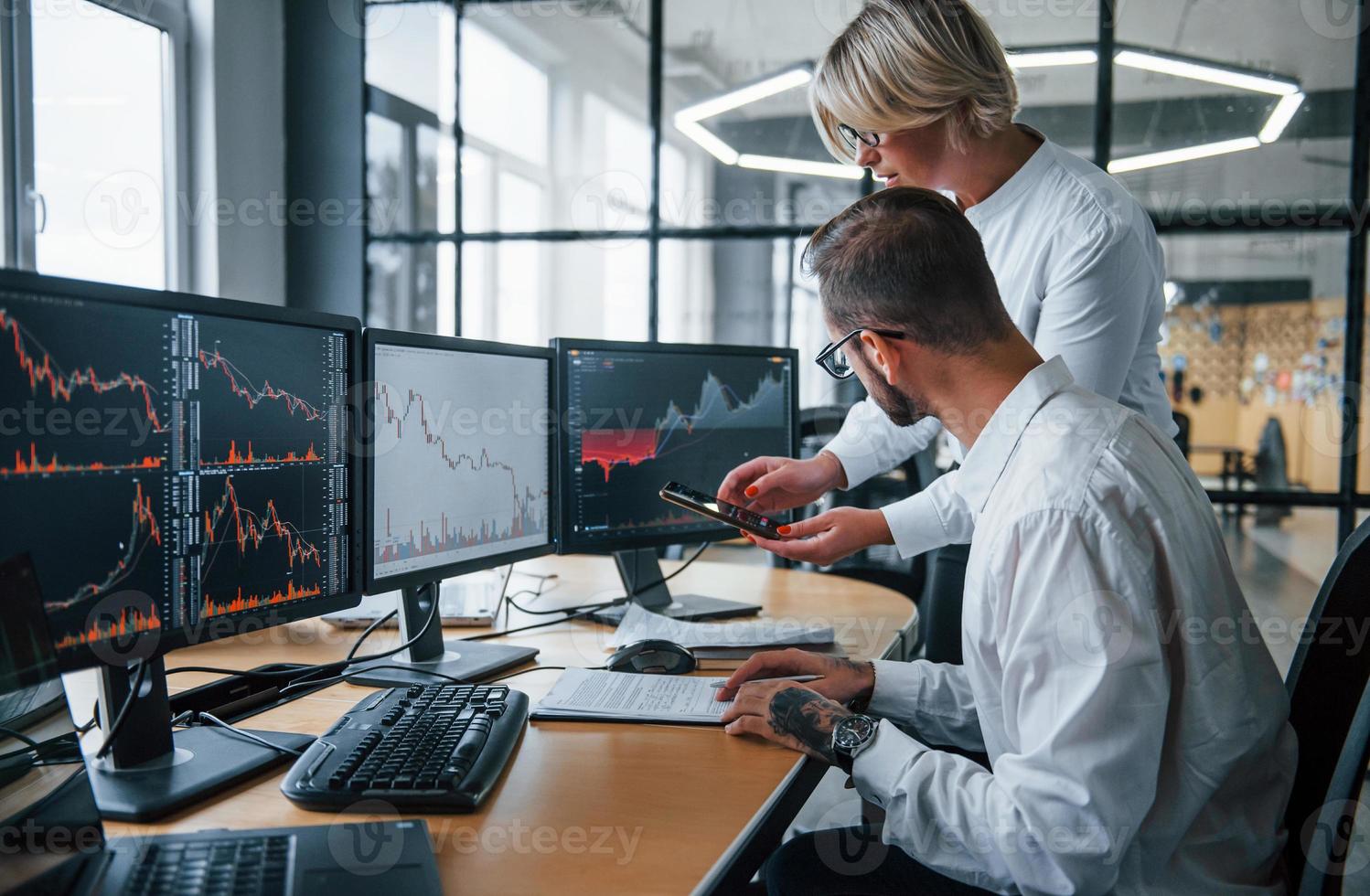 Informationen gemeinsam analysieren. zwei börsenmakler in formeller kleidung arbeiten im büro mit finanzmarkt foto