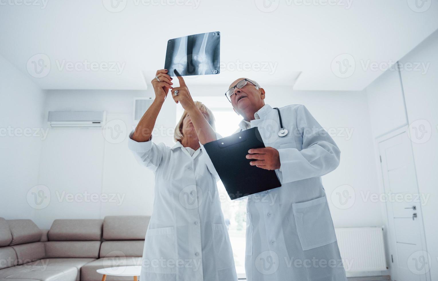 hochrangige Ärztinnen und Ärzte in weißer Uniform untersuchen Röntgenbilder menschlicher Beine foto