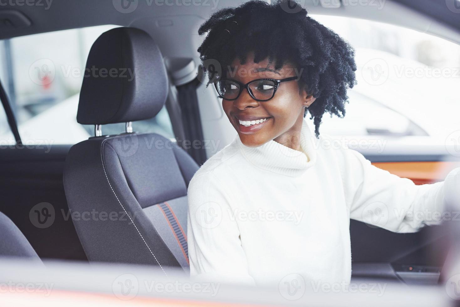 junge afroamerikanische frau sitzt im neuen modernen auto foto