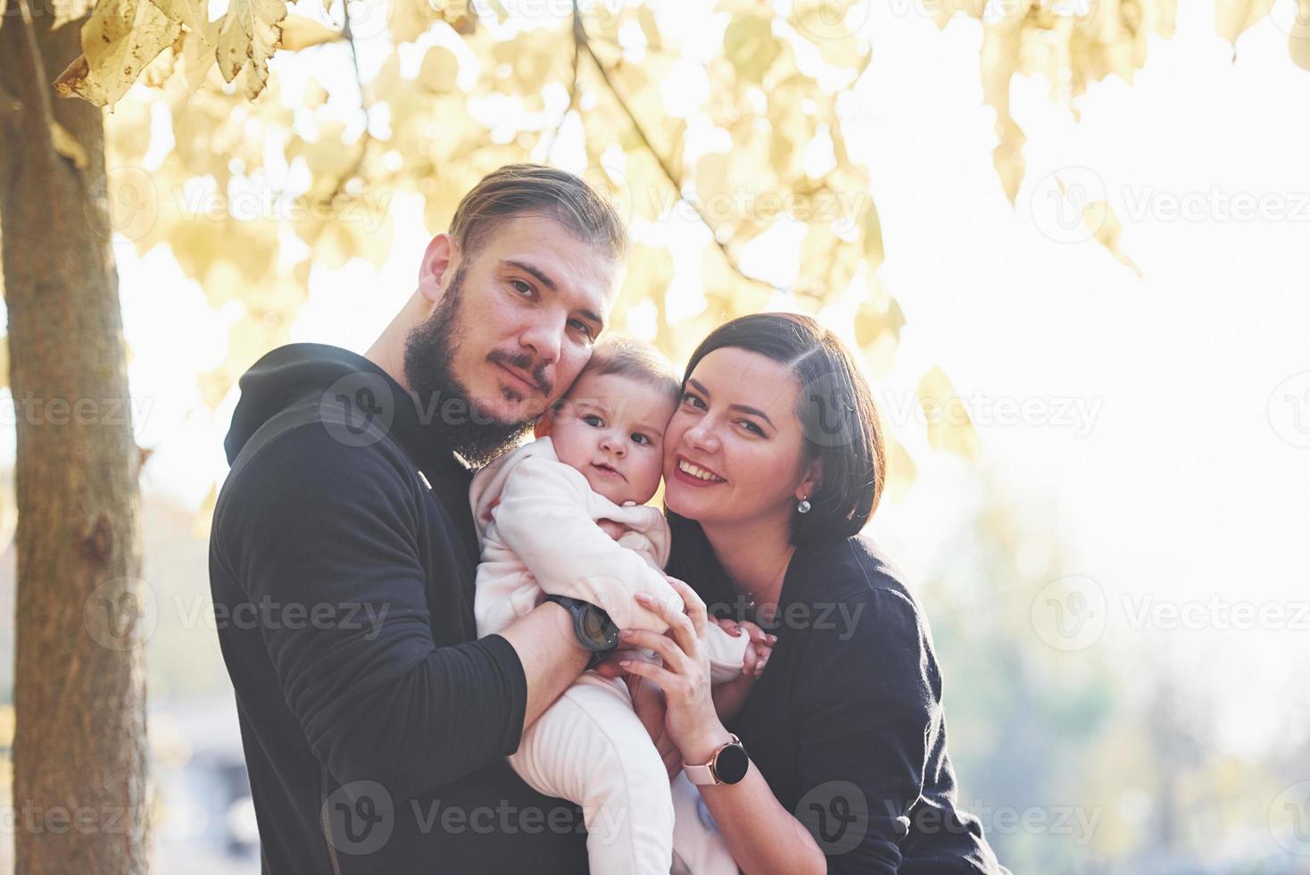 Fröhliche Familie geht zusammen mit ihrem Kind im Park spazieren foto