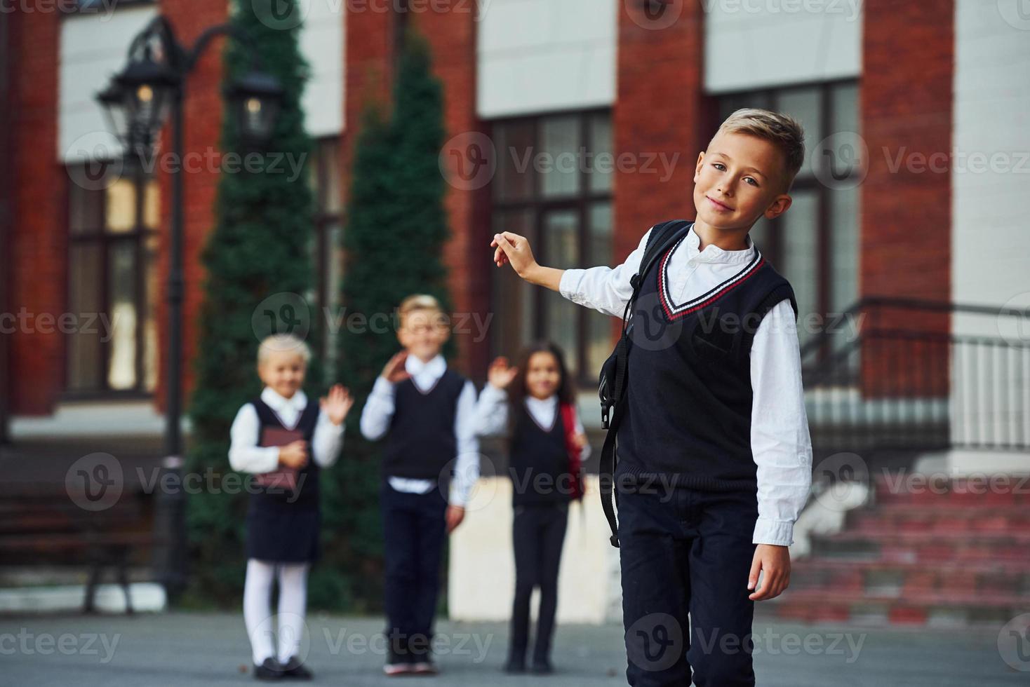 gruppe von kindern in schuluniform, die zusammen vor der kamera im freien in der nähe des bildungsgebäudes posieren foto