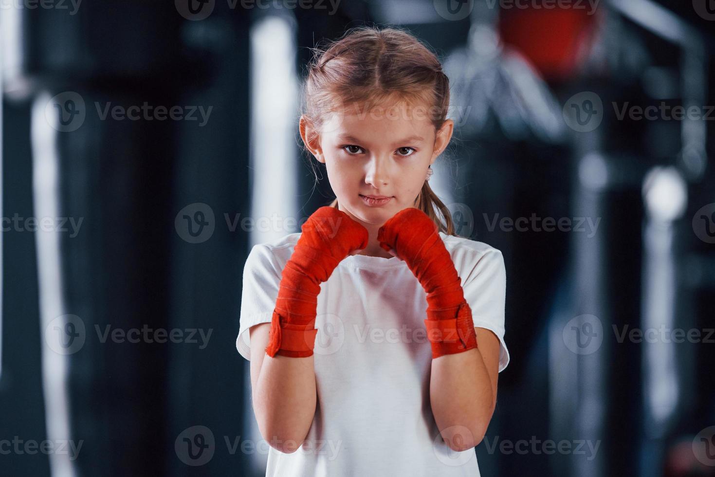 porträt eines jungen kleinen mädchens in sportlicher kleidung, das im fitnessstudio ist, hat einen trainingstag. Konzeption des Boxens foto