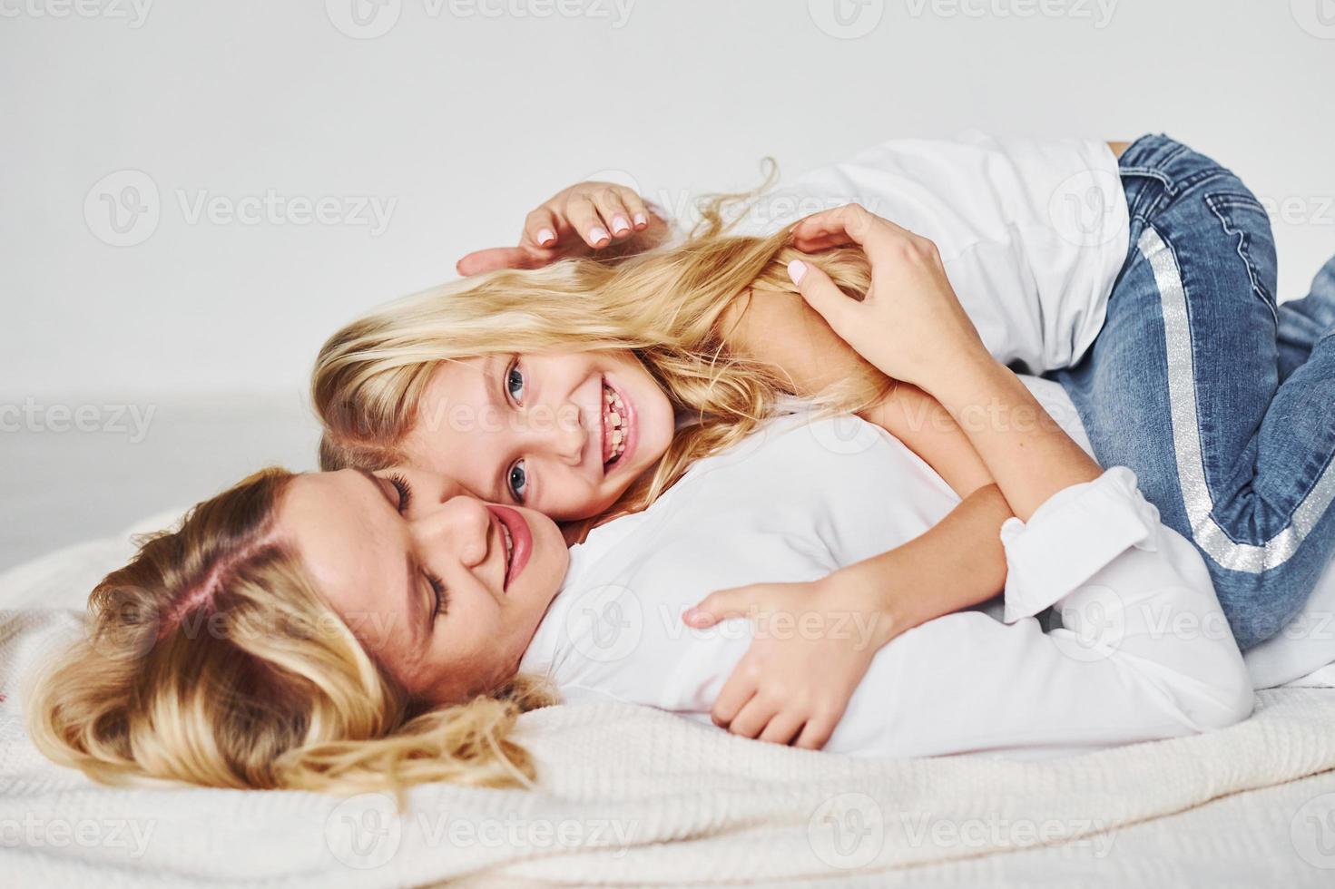 mutter mit ihrer tochter zusammen ist auf dem boden im studio mit weißem hintergrund foto